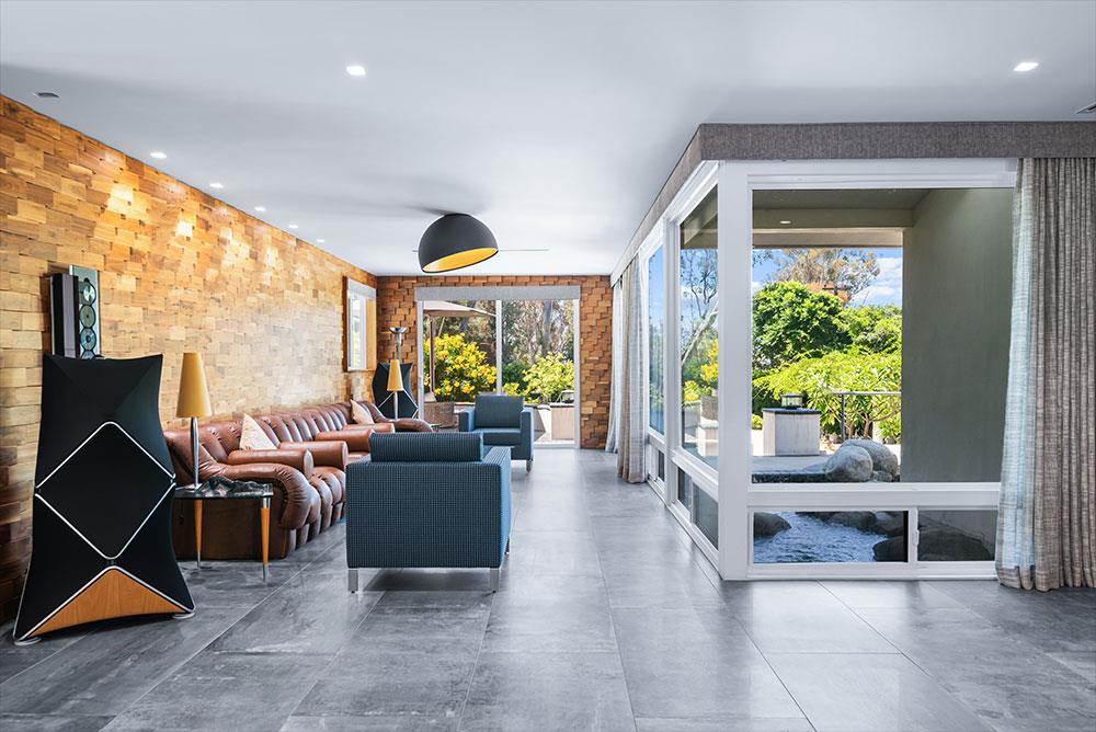 Living room with a wood accent wall and glass walls to the garden